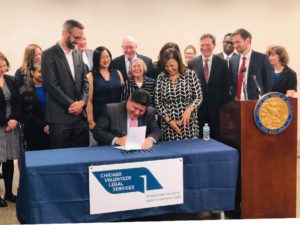 Pictured: State Rep. Theresa Mah (first row, center left) joins Gov. J.B. Pritzker, state Rep. Will Guzzardi, former House Majority Leader Barbara Flynn Currie, and state Sen. Iris Martinez at the signing of the Consumer Fairness Act.
