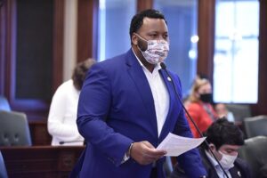 A photograph of State Representative Kam Buckner speaking on the House floor